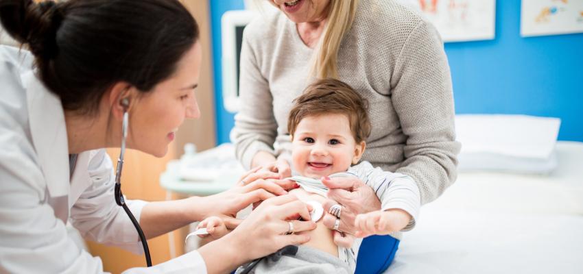 Médica atendendo um bebê acompanhado de sua mãe